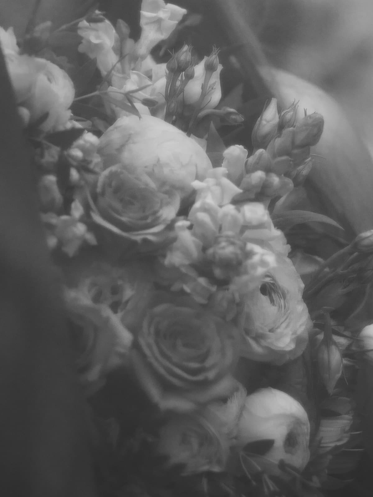 The bouquet under the veil, close — roses and ranunculus in black and white