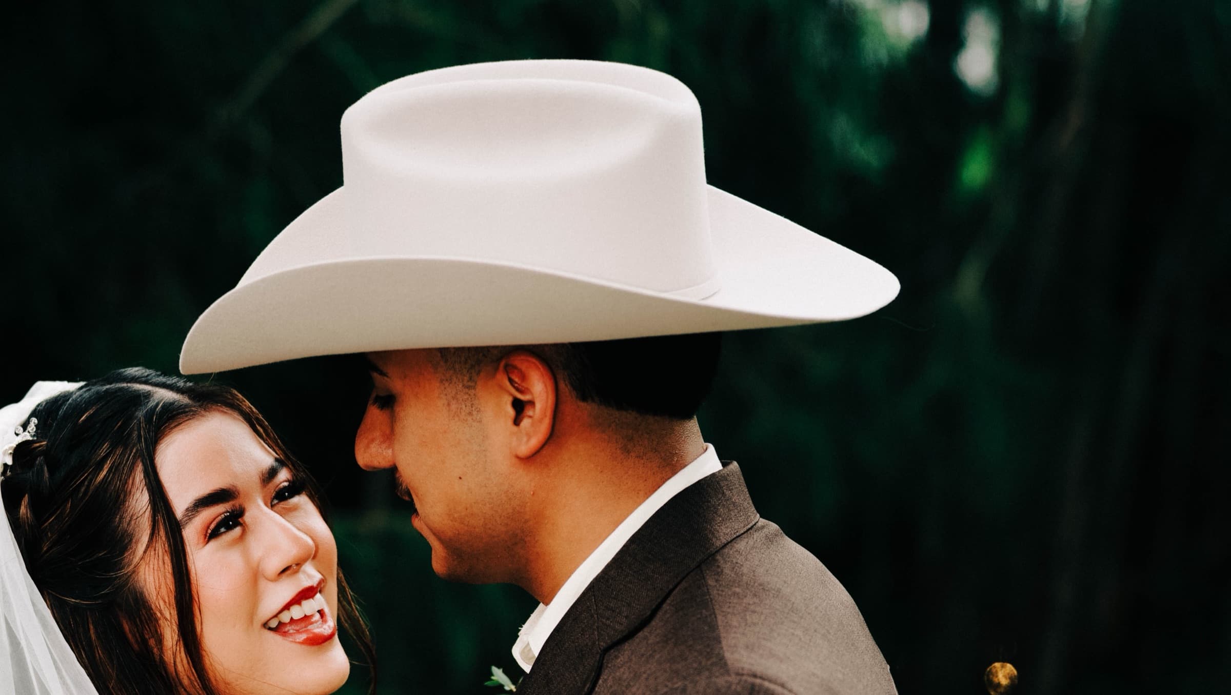 The bride and groom, close together under the brim of his hat